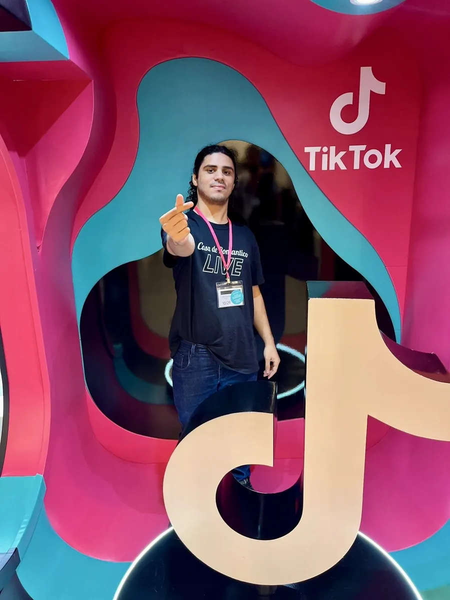 Arthur, do suporte administrativo da Casa de Romantico LIVE, no escritório do TikTok com a camiseta da agência e o crachá de visitante